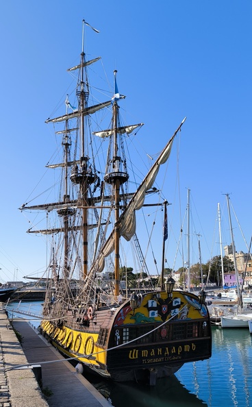 La poupe de la frégate Le Shtandart est un des éléments les plus impressionnants et décoratifs de ce navire, fidèle réplique d'une frégate russe du XVIIIe siècle. Ce bateau, construit à l'origine sous le règne de Pierre le Grand en 1703, servait de vaisseau amiral de la première flotte russe.La poupe du Shtandart est ornée de sculptures et de motifs complexes dans un style baroque caractéristique des navires de guerre de l'époque. On y retrouve souvent des éléments symboliques et décoratifs, tels que des figures mythologiques, des symboles de pouvoir, des ornements dorés et des armes russes. Cet art de la sculpture vise à montrer la puissance et le prestige de la marine impériale russe. Le blason de l'aigle bicéphale de la Russie impériale est aussi souvent présent sur ces types de navires, symbolisant l'autorité du Tsar sur l'Est et l'Ouest.La frégate moderne Shtandart, construite en 1999 comme réplique historique, a reproduit ces éléments avec une grande fidélité, ce qui en fait un navire unique et spectaculaire. Frégate Le Shtandart port de La Rochelle.jpg